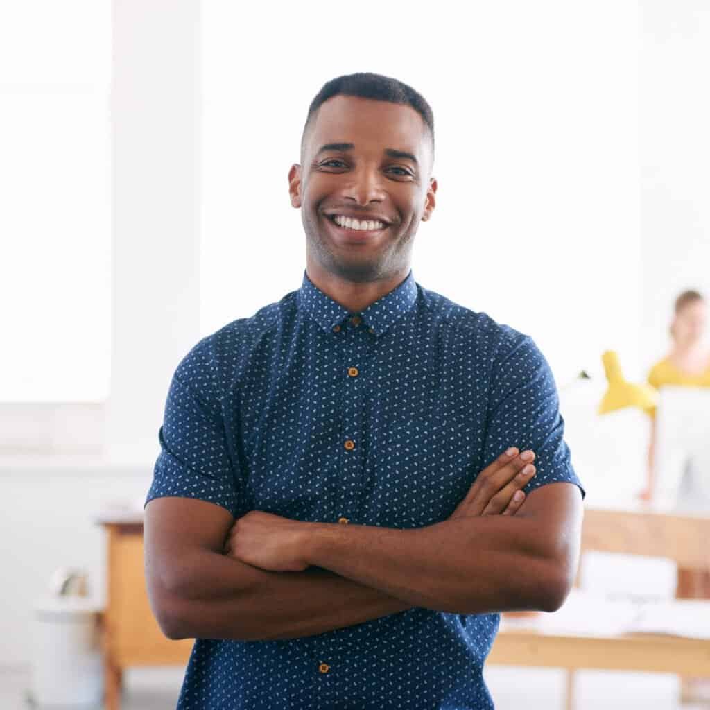Smiling man with crossed arms in a bright, modern space.